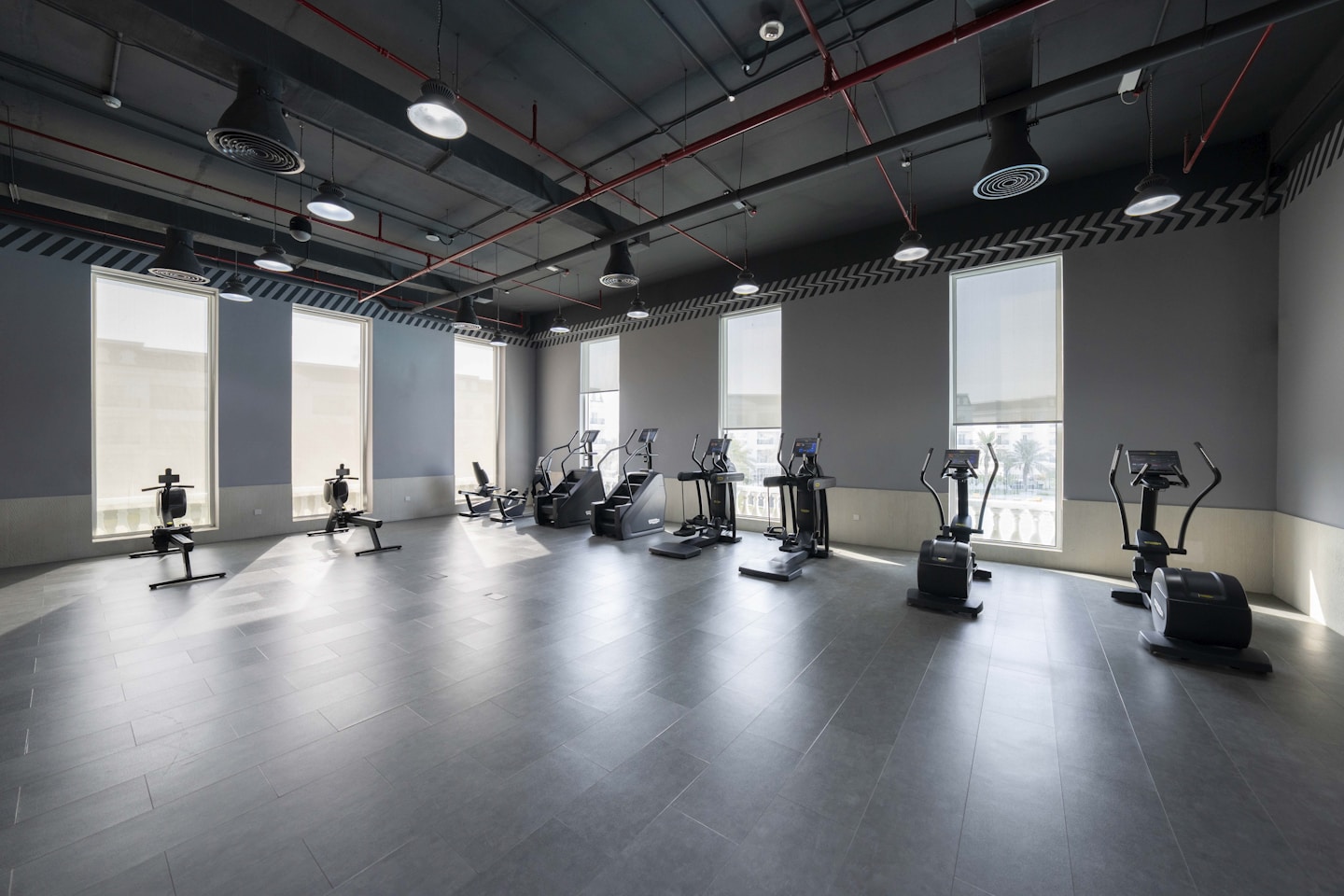 Commercial workout gym interior with cardio machines and large windows